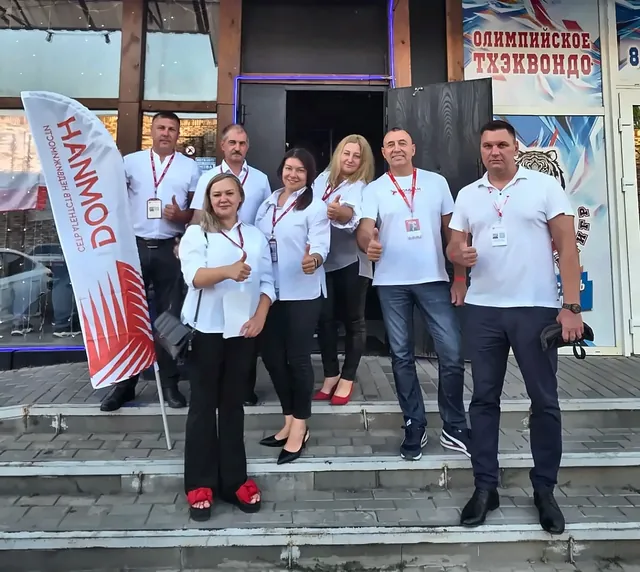 Команда офиса Домиан с брендированным флагом на улице